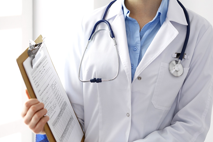 Female Doctor Filling Up Medical Form On Clipboard Closeup