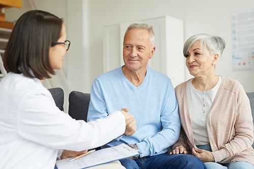 Portrait of smiling senior couple shaking hands with female doctor while visiting private clinic