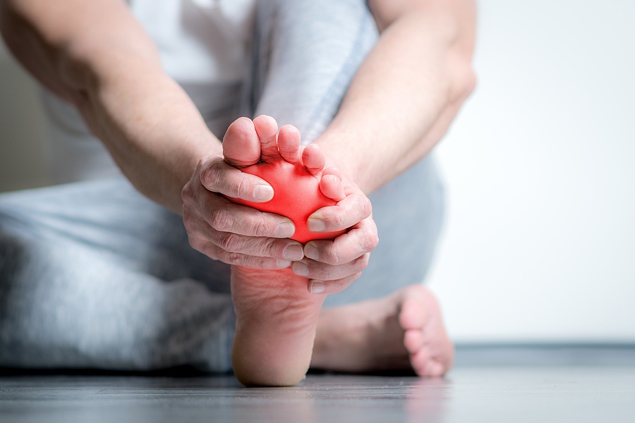 Causian Man Holds Hands To His Painful Feet, Pain In Foot, Red C man holds hand to foot pain