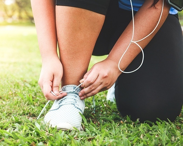 person tying a sneaker before exercising