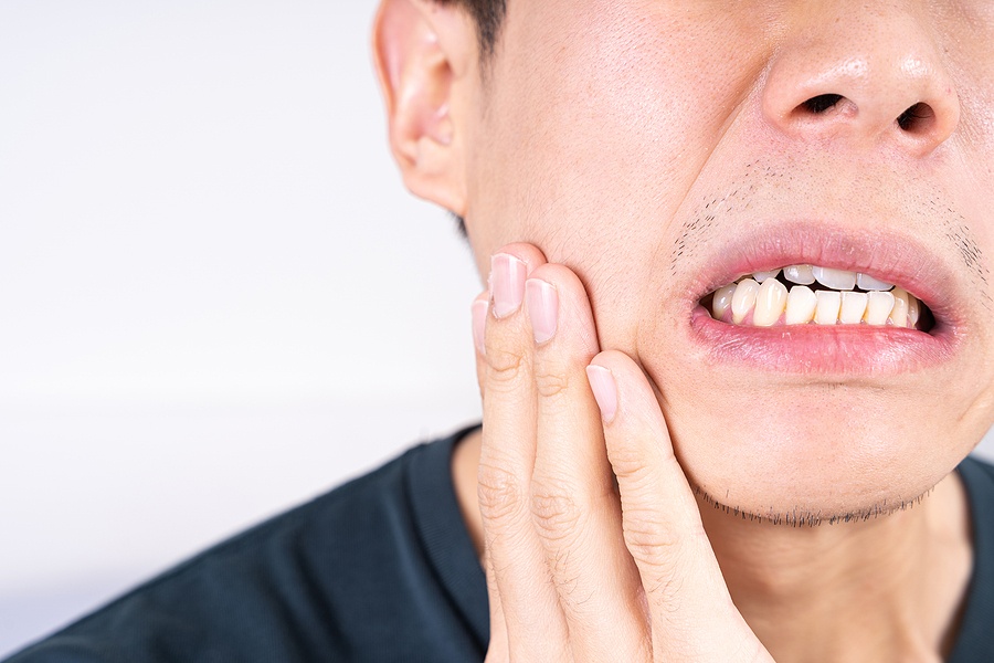 man holding his mouth in pain