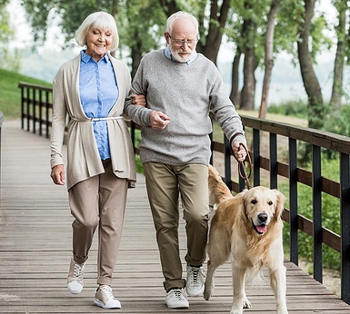 happy senior couple walking their dog