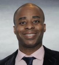 Photo of Joseph Bidjoka, smiling, wearing a suit and tie