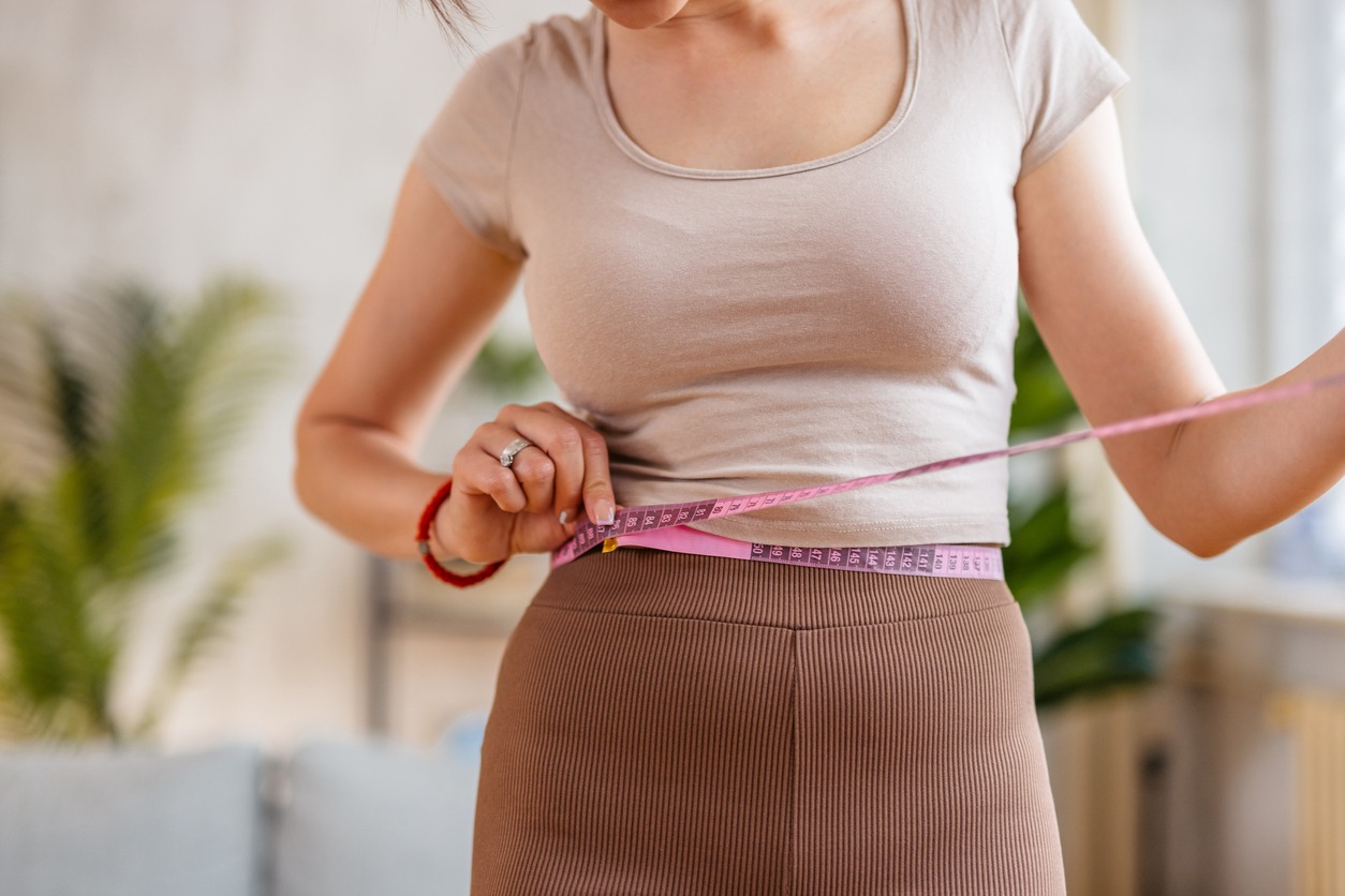 adult woman measuring her waist with a measuring tape