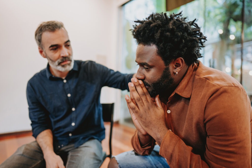 male caregiver being comforted by a male friend