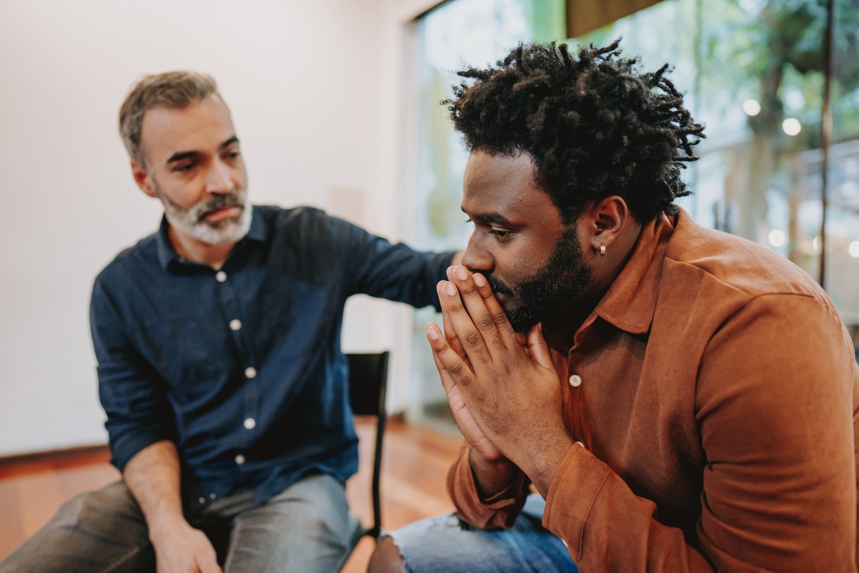 male caregiver being comforted by a male friend male caregiver being comforted by a male friend