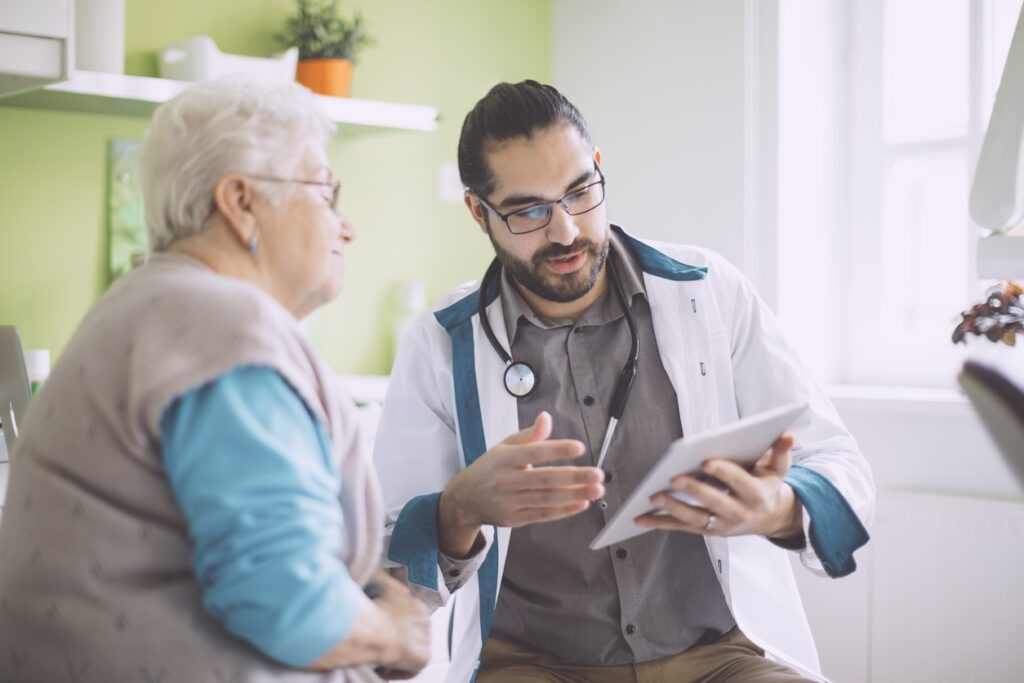 senior woman reviewing a tablet with a doctor in exam room