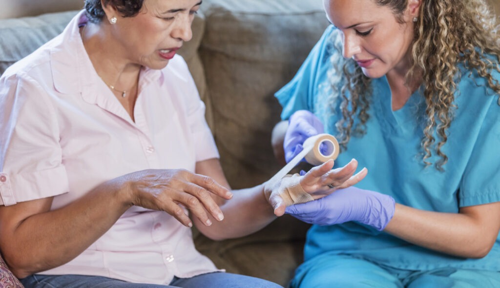 Nurse wrapping bandage on woman's hand