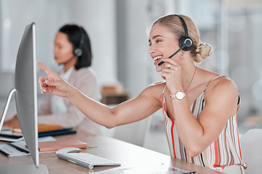 Customer support representative speaking through a headset while working at a computer.